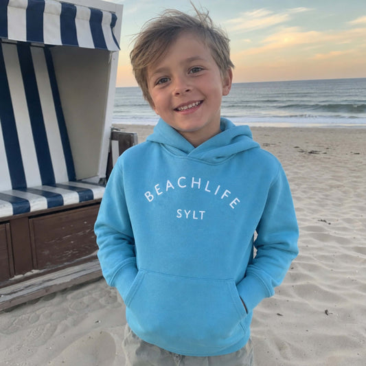 Kind am Strand mit blauem Sylt Hoodie